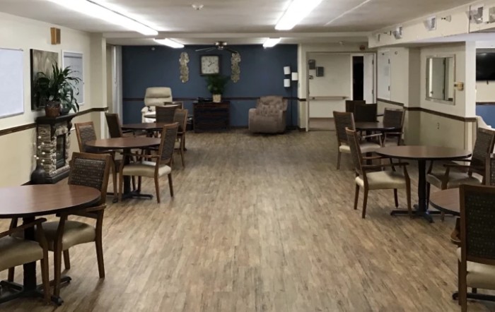 A spacious dining area with wooden flooring and multiple tables and chairs.