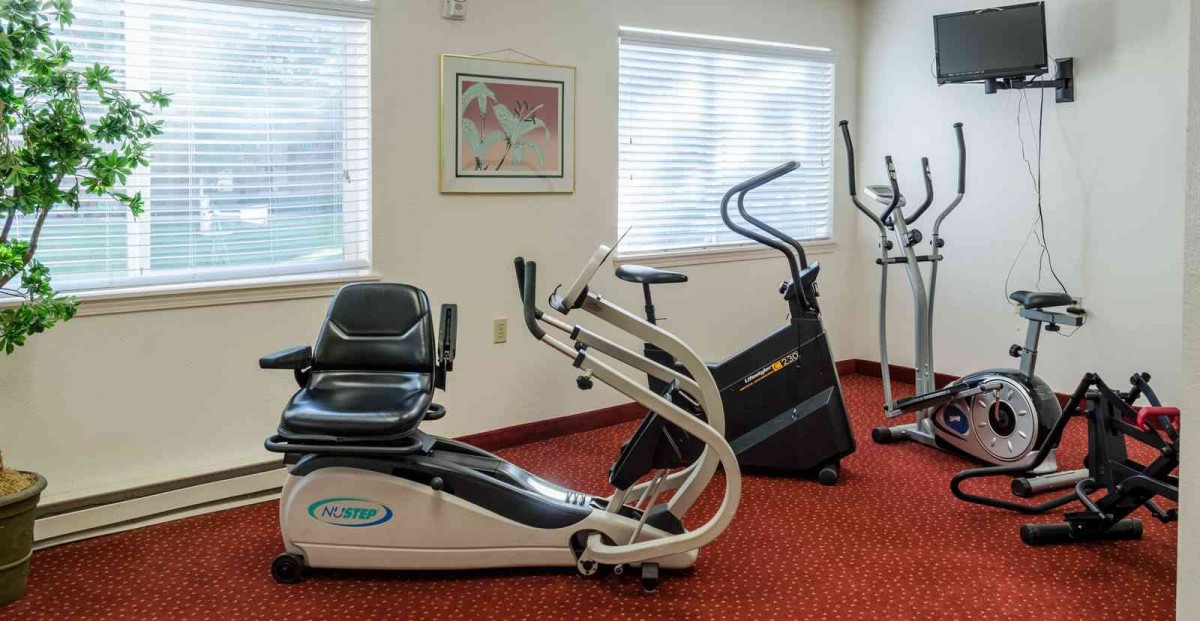 A fitness room with stationary exercise equipment including a bike and elliptical machine.