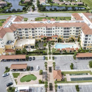 Aerial view of a residential apartment complex with a large central pool and landscaped surroundings.
