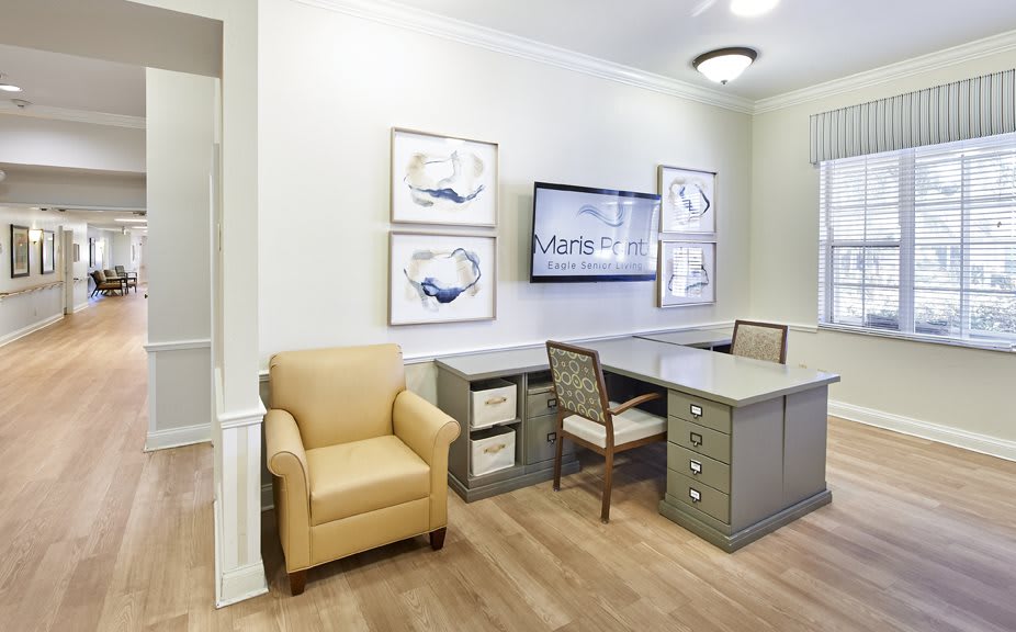 A modern office space with a desk, chair, and wall-mounted screen.