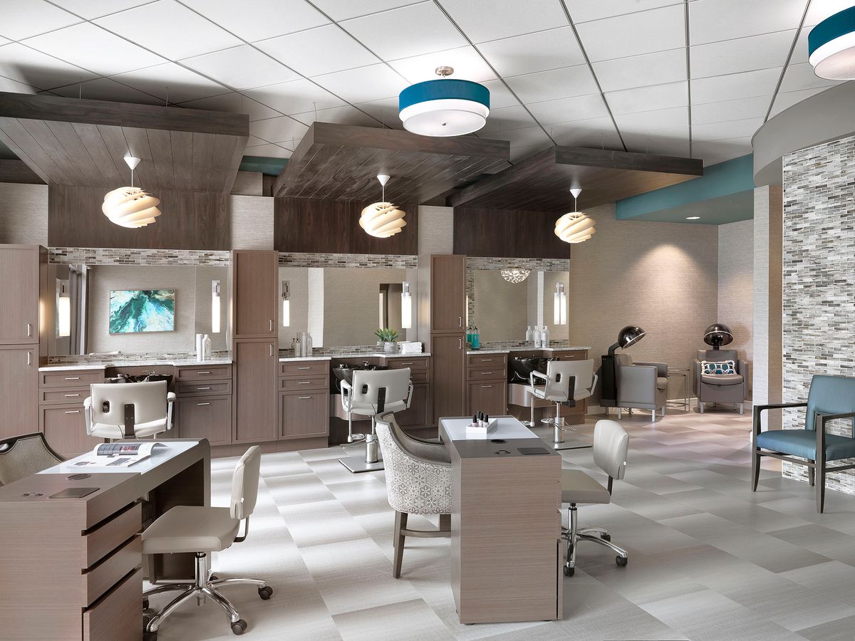 A modern beauty salon featuring sleek workstations, comfortable chairs, and stylish lighting.