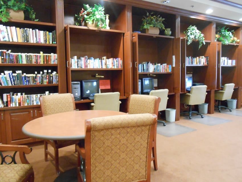 A cozy library area with bookshelves, computers, and seating for reading and studying.