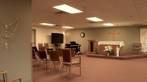A quiet chapel setting featuring chairs arranged for a service, a pulpit, and a piano.