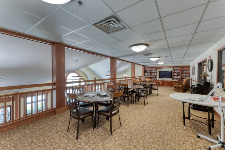 A quiet reading area in a library with tables, chairs, and bookshelves.