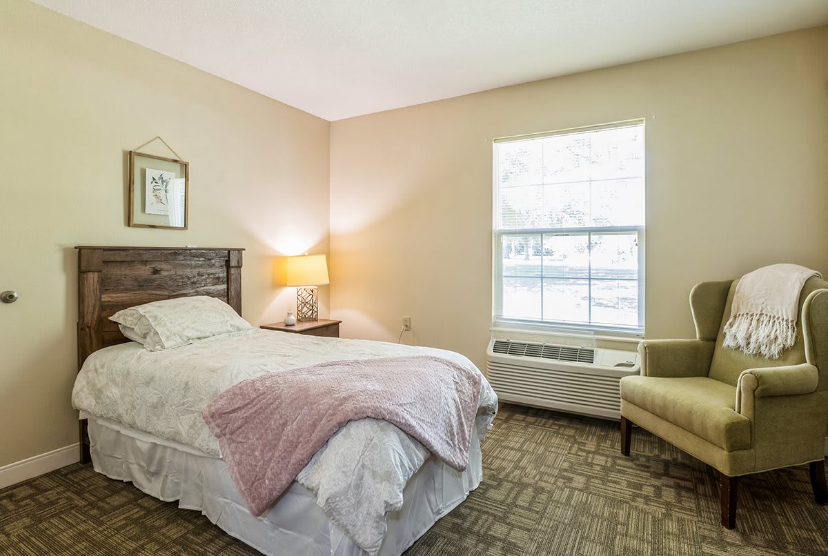 A cozy bedroom with a single bed, bedside lamp, and window.