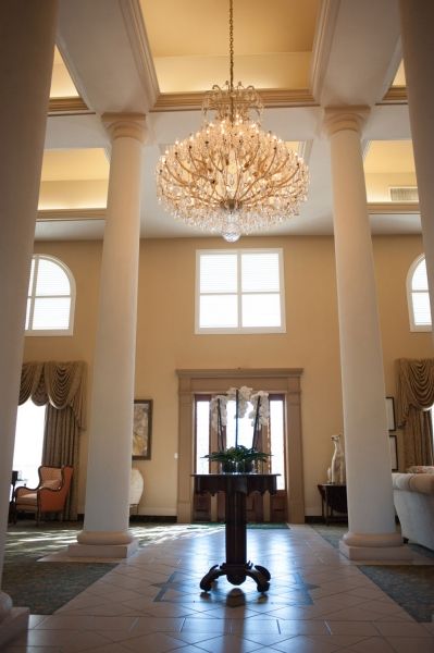 Elegant entrance with grand chandelier and classic columns.