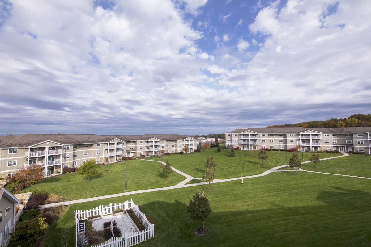 A residential area featuring multiple apartment buildings surrounded by green lawns and walkways under a cloudy sky.