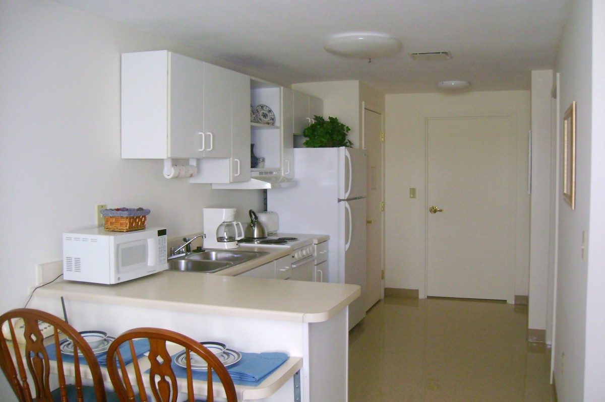 A compact modern kitchen with white cabinets and appliances.