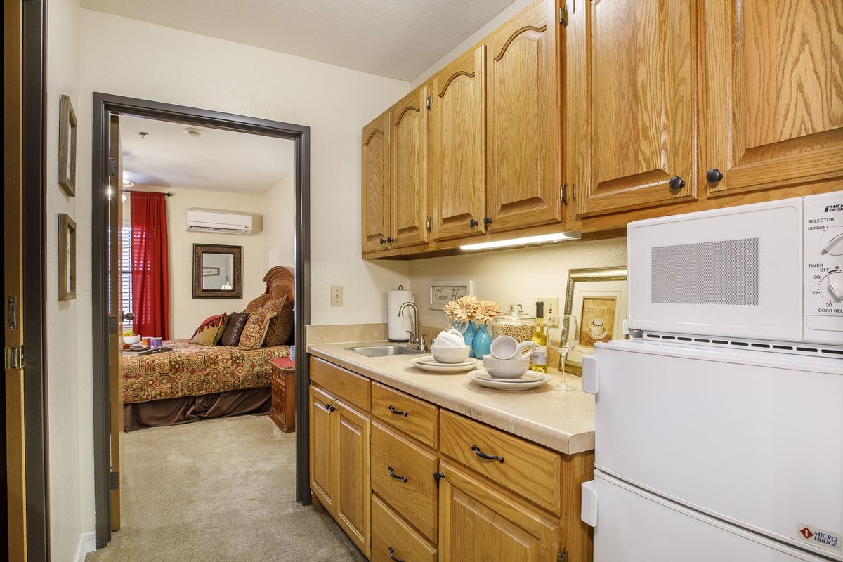 A cozy kitchen area adjacent to a living room with warm wooden cabinets and modern appliances.
