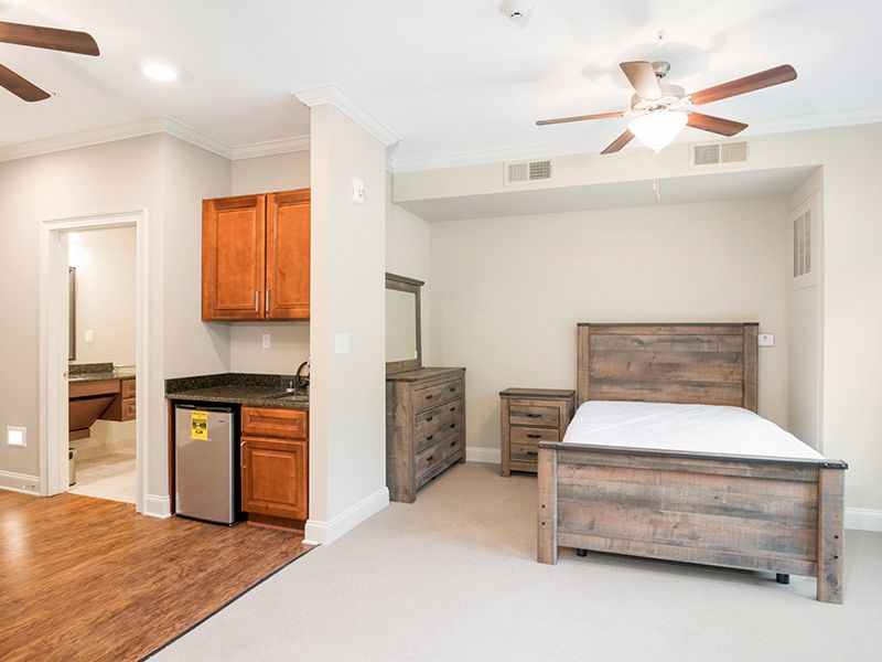 A modern bedroom with wooden furniture and a mini fridge.