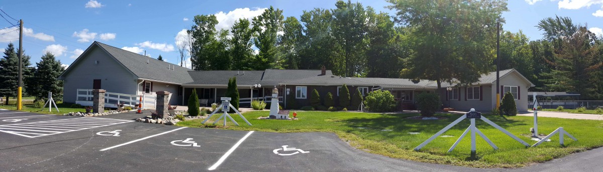 A single-story house with a well-maintained lawn and garden decor, featuring a handicapped parking spot in the driveway.
