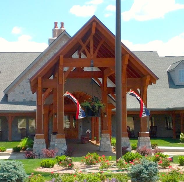 A beautifully designed building entrance with a wooden structure and well-maintained landscaping.