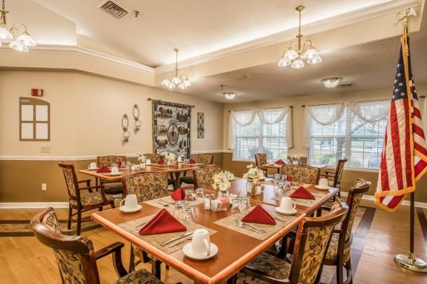 A well-decorated dining room with neatly arranged tables and chairs, featuring elegant lighting and tableware.