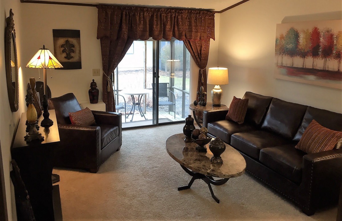 A cozy living room with a sofa, armchair, and coffee table, featuring warm lighting and elegant decor.
