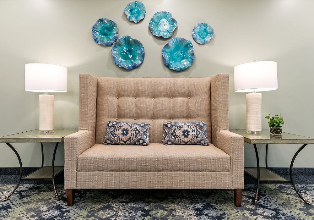A cozy seating area with a tufted sofa, embellished by decorative pillows and vibrant wall art.