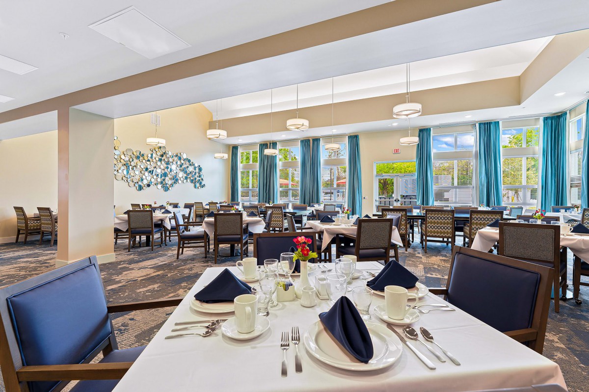 A beautifully set dining area in a restaurant with elegantly arranged tables and chairs, featuring neatly folded napkins.