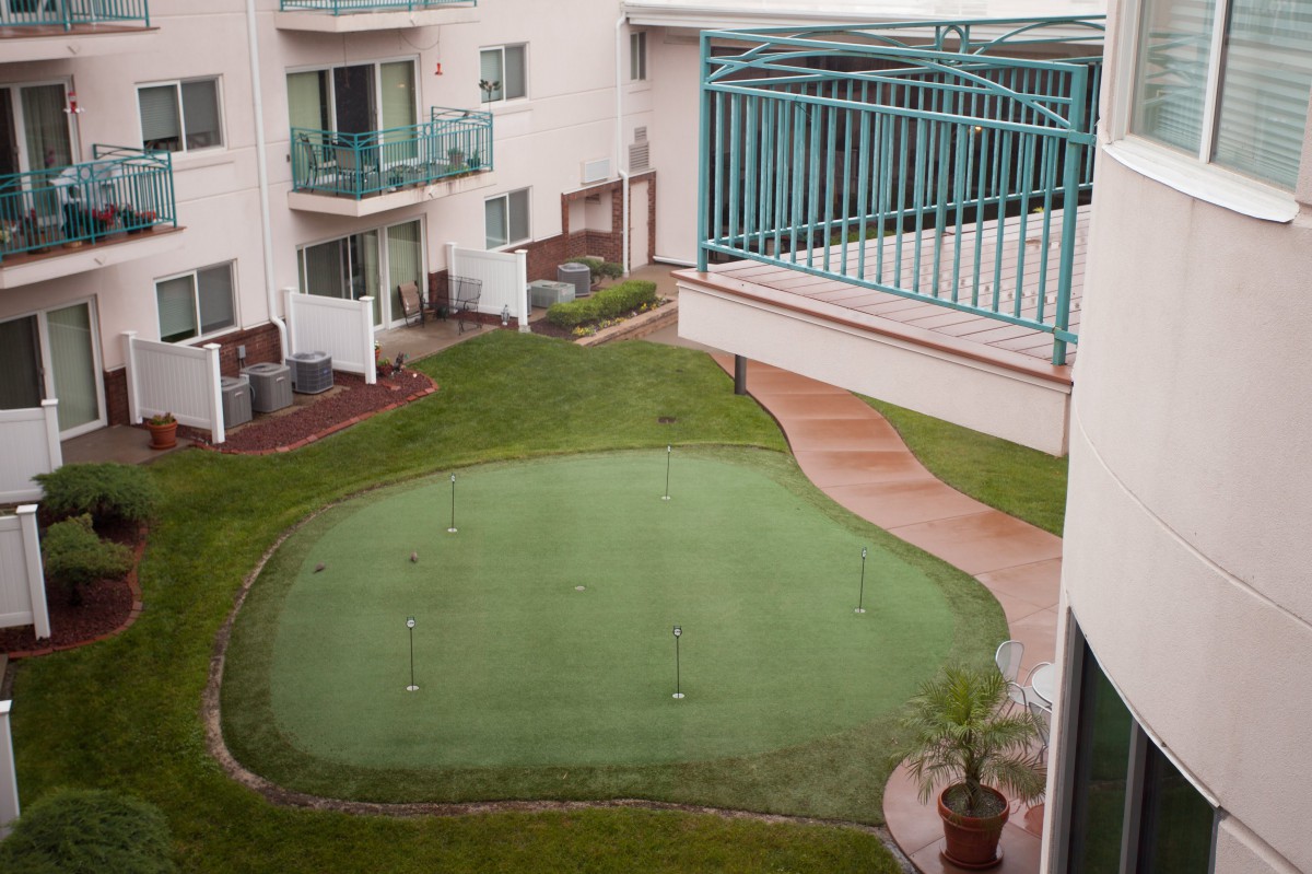 A putting green located in a courtyard surrounded by apartment buildings.