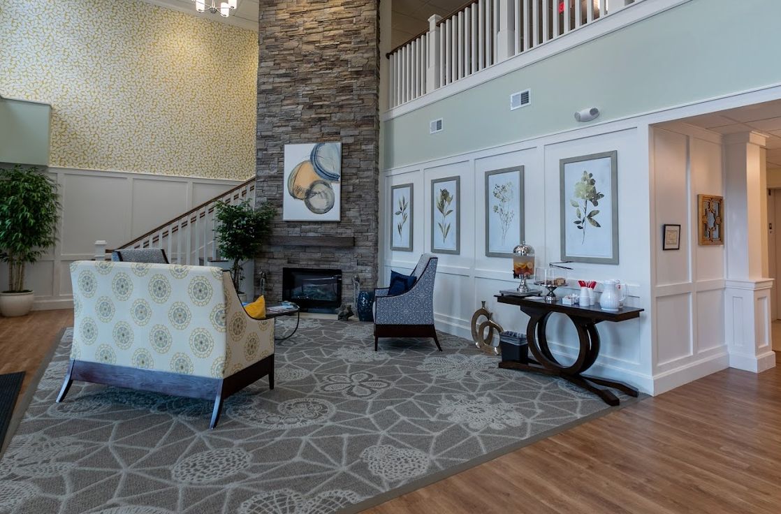 A cozy and modern living room featuring a stone fireplace, stylish furniture, and decorative artwork.