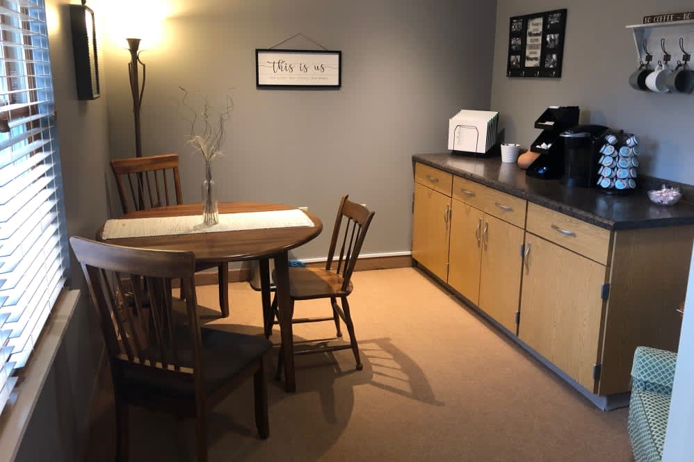 A cozy dining area with a wooden table and chairs, accompanied by cabinets and a lamp.