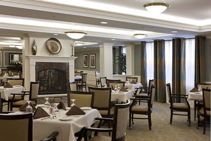 A well-lit dining area with neatly arranged tables and chairs, featuring elegant decor.