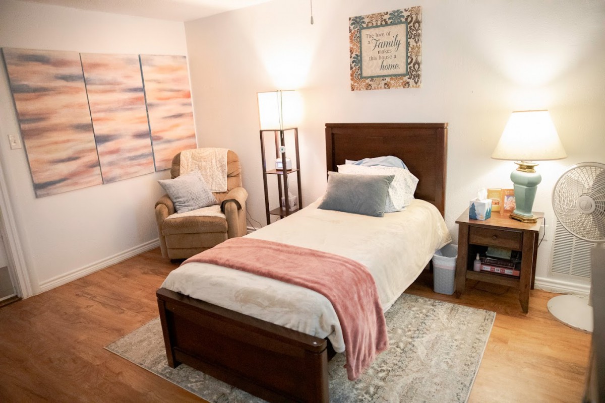 A cozy bedroom with a single bed, armchair, and soft lighting.