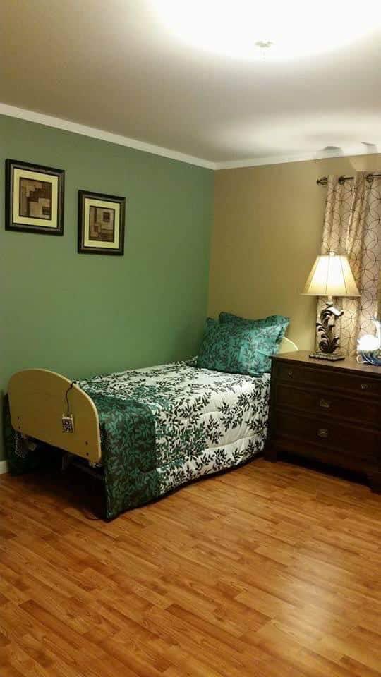 A cozy bedroom with a single bed, green walls, and decorative elements.
