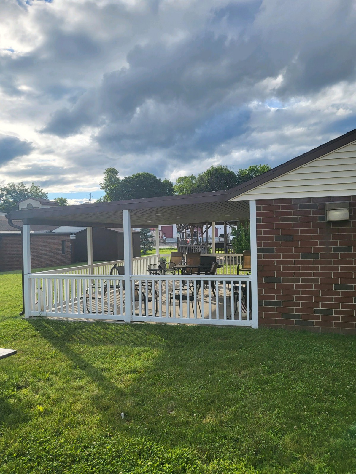 A backyard patio with a white fence and a gazebo on a sunny day.