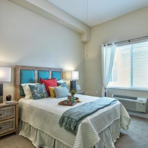 A cozy and well-decorated bedroom featuring a comfortable bed, colorful pillows, and ambient lighting from bedside lamps.