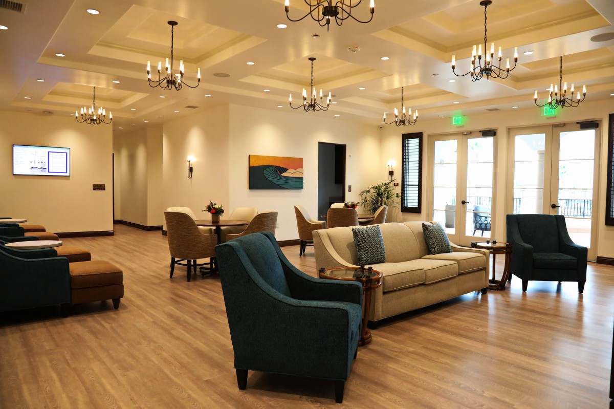 A beautifully decorated living space featuring cozy sofas, armchairs, elegant chandeliers, and modern artwork on the walls.