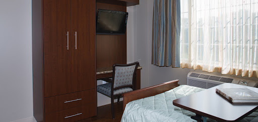 A cozy bedroom featuring a wooden bed, desk, and a television.
