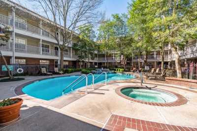 A tranquil outdoor swimming pool and hot tub surrounded by trees and an apartment complex.
