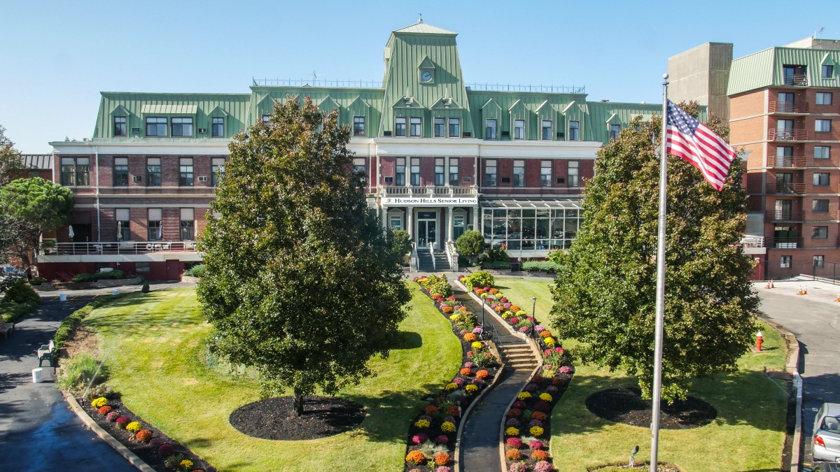 A historical building with a beautifully landscaped garden in front.