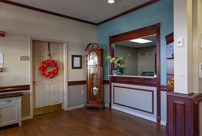 A cozy waiting room with a grandfather clock and decorated wreath.