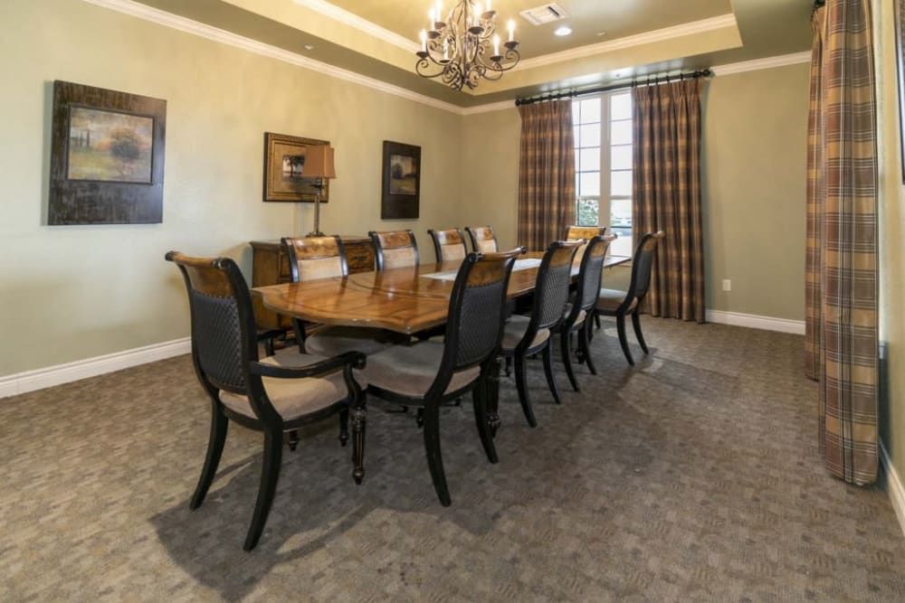 A spacious dining room featuring a long table with elegant chairs and a chandelier overhead.