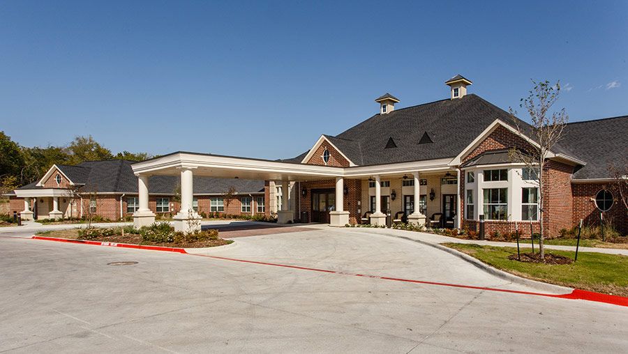 A large building with a covered entrance and columns set against a clear blue sky.