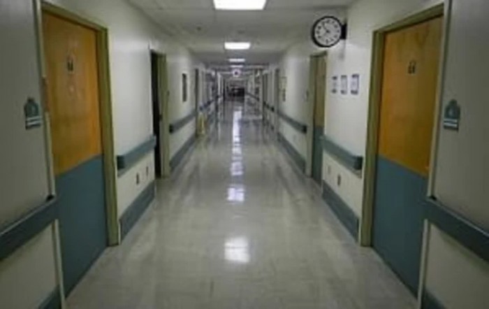 An empty hospital corridor with fluorescent lighting.