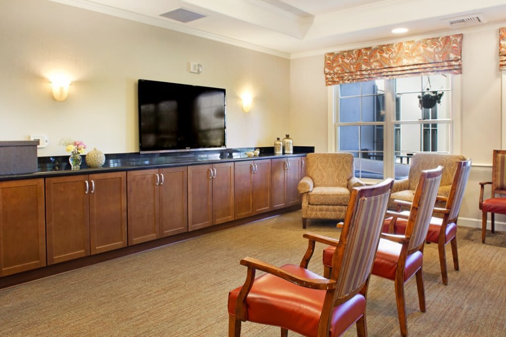 A comfortable living room with chairs arranged in front of a large television and wooden cabinets.
