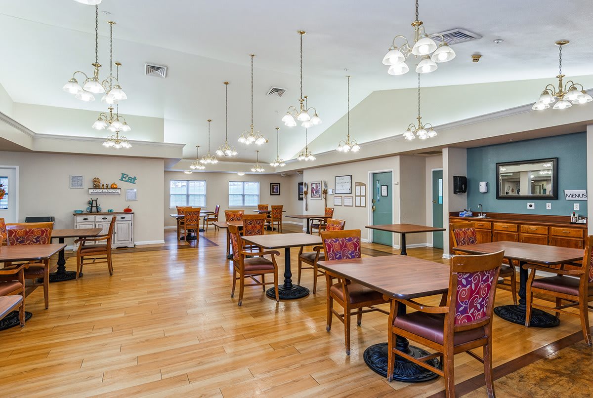 A spacious dining area with wooden floors and well-arranged tables and chairs.