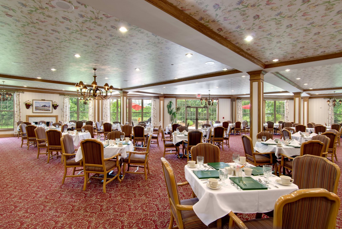 An elegant dining room with neatly arranged tables and chairs, adorned with chandeliers.
