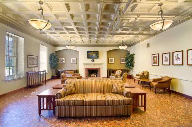 A spacious lounge area featuring a striped sofa, fireplace, and elegant ceiling lights.