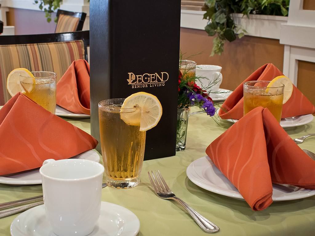 An elegantly set dining table with iced tea garnished with a lemon slice and neatly folded napkins.
