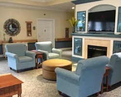 A cozy living room with armchairs, a fireplace, and a television.