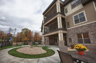 A modern apartment building surrounded by fall foliage and well-maintained landscaping.