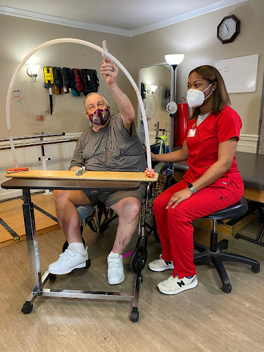 A healthcare professional assists a patient during a therapy session, focusing on rehabilitation exercises.