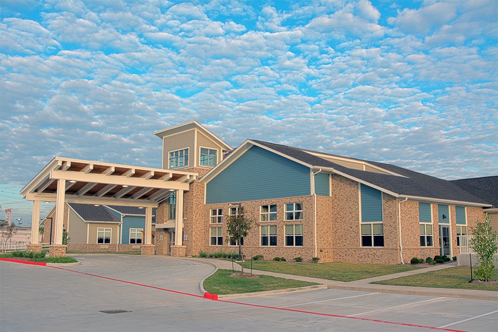 A modern school building with a covered driveway under a cloudy sky.
