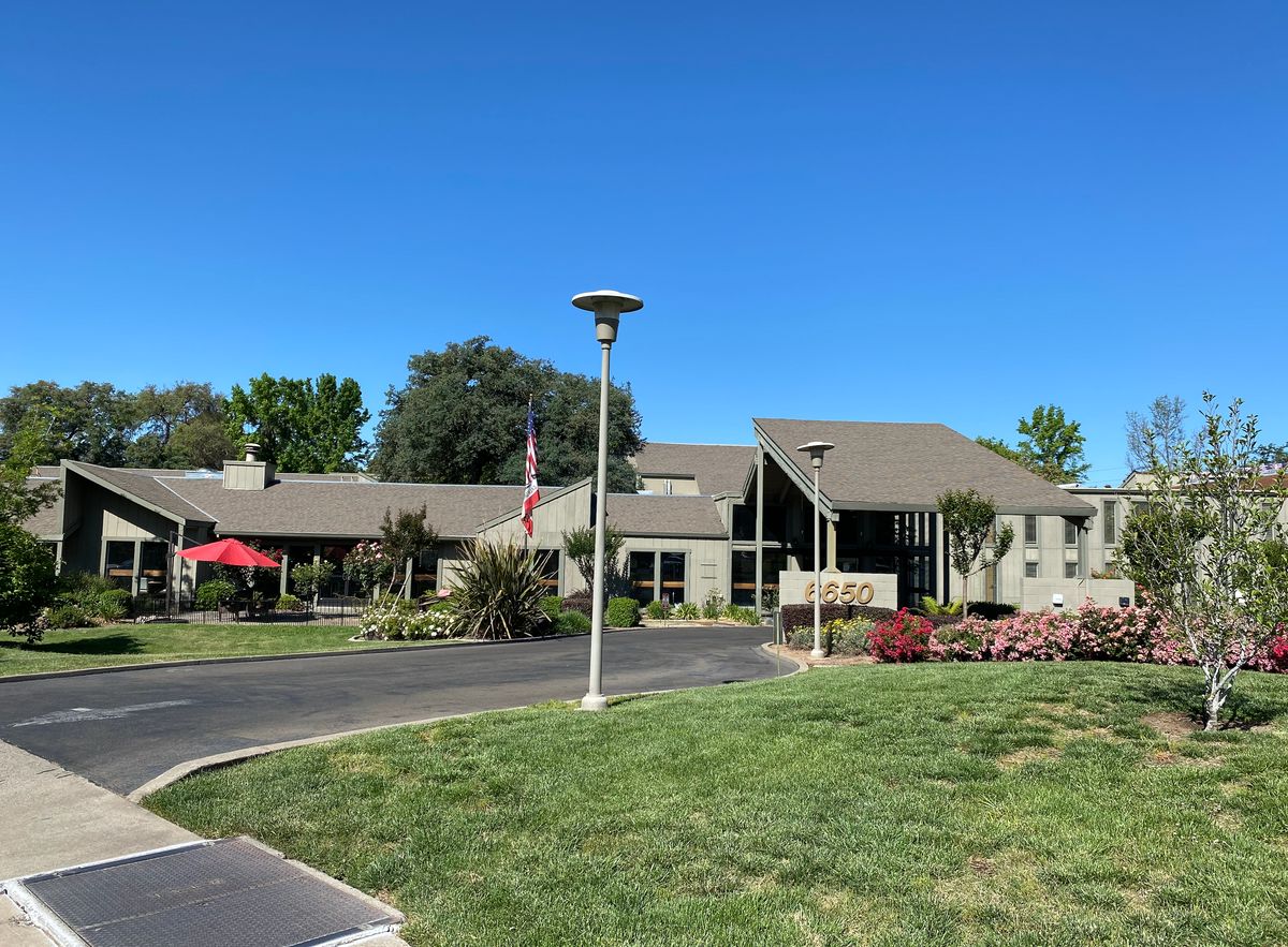 A scenic view of a residential building with a well-maintained lawn and clear blue sky.