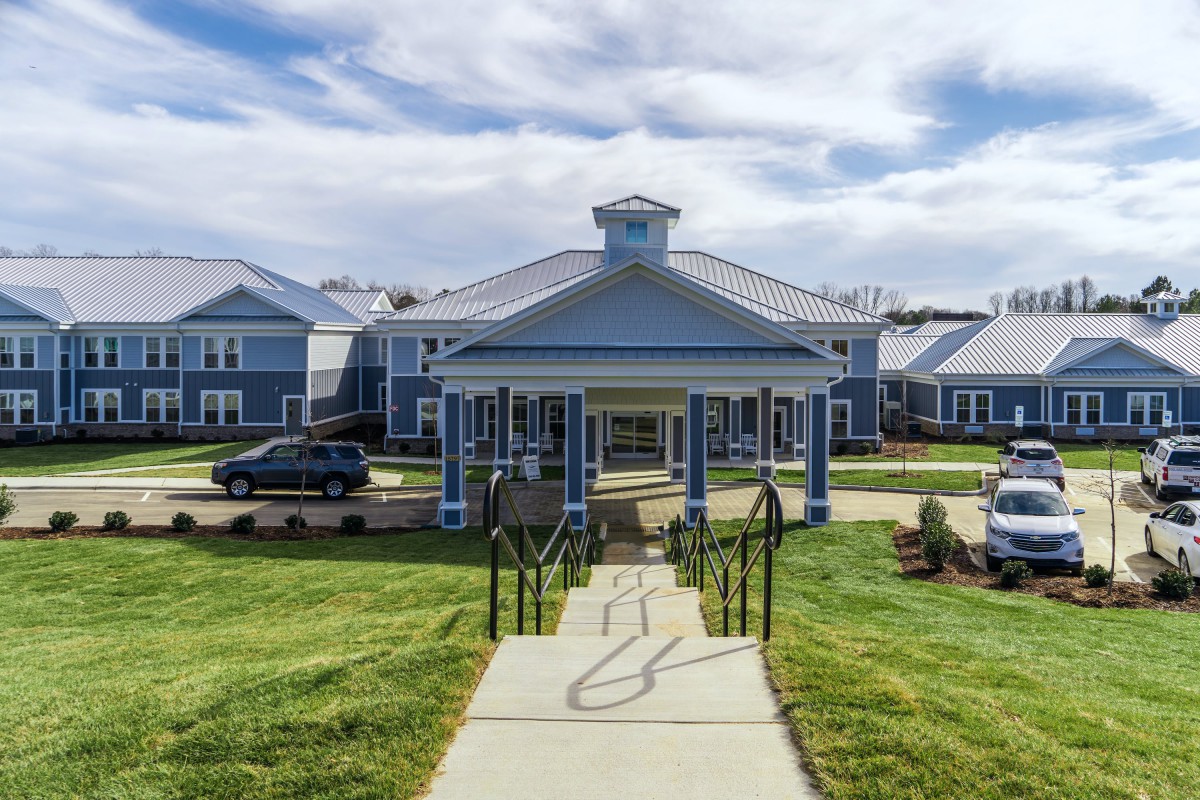A building with a portico entrance and surrounding landscape.