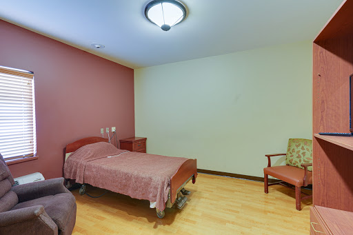 A simple and clean hospital room featuring a single bed and a chair.
