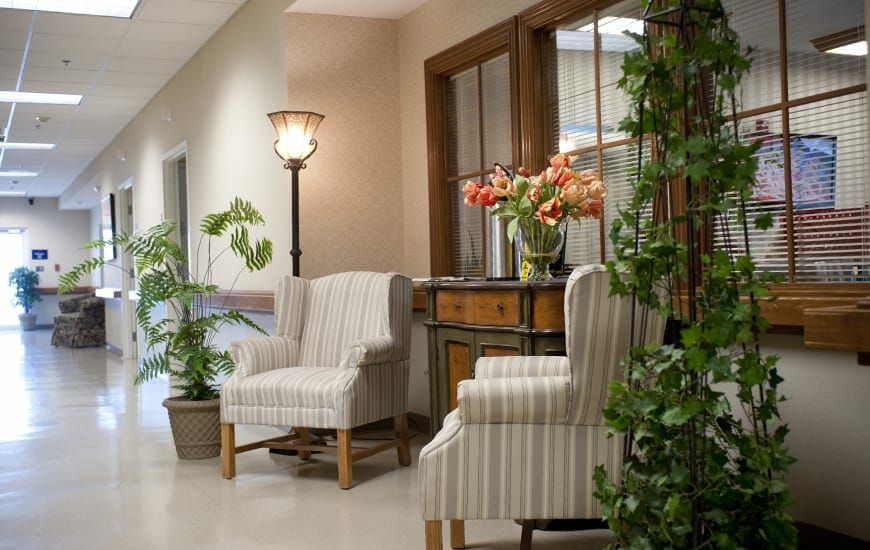A cozy hallway with striped chairs, a decorative table adorned with flowers, and greenery for a welcoming atmosphere.