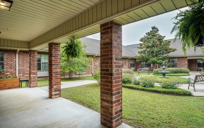 A serene courtyard featuring brick columns and lush greenery.